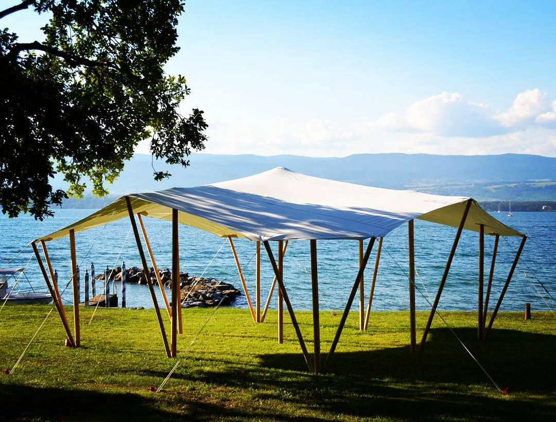Toile nomade tendue sur ses poteaux de bois au bord du lac Léman, montagnes au fond
