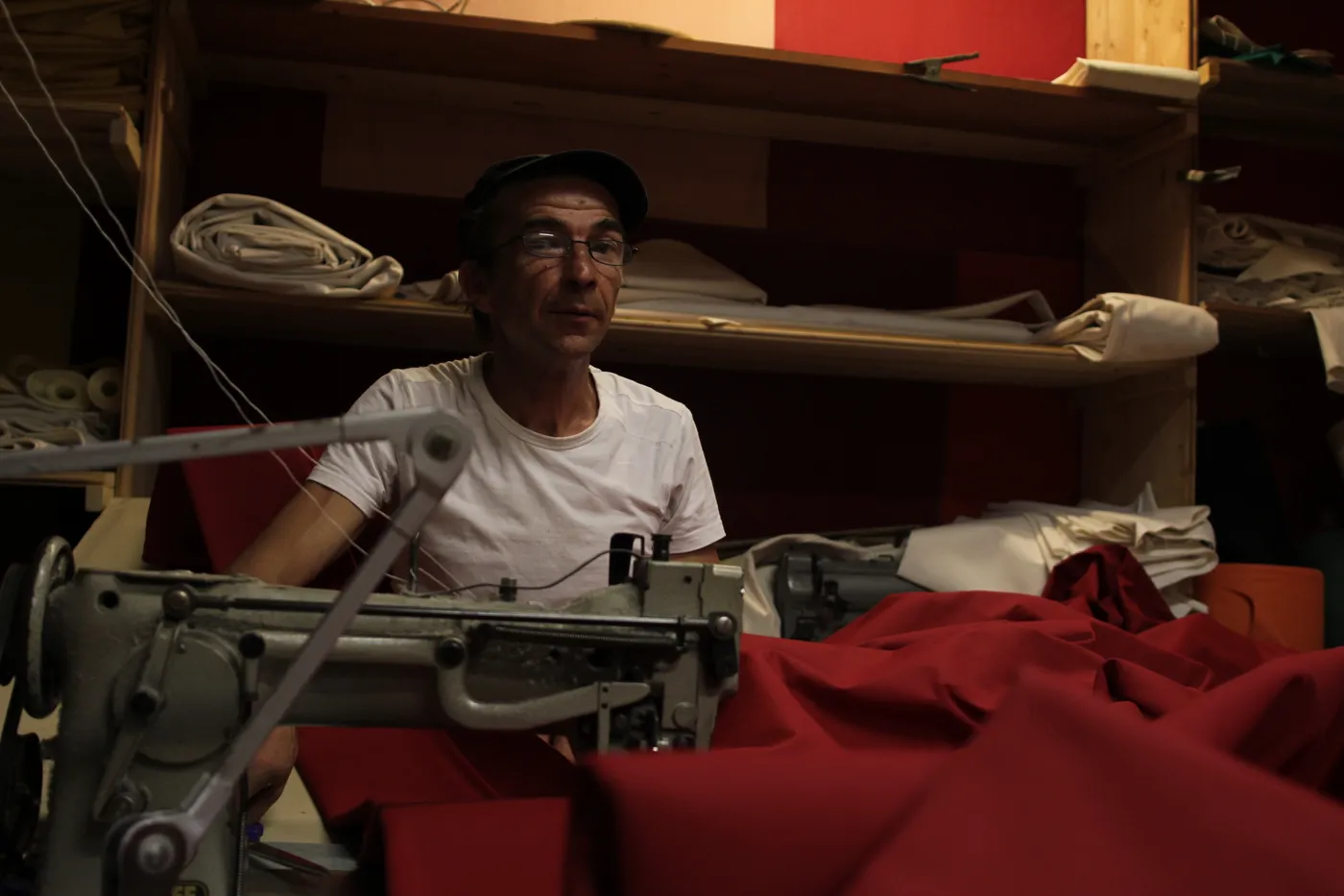 Couturier de l'atelier travaillant une toile rouge sur une machine industrielle
