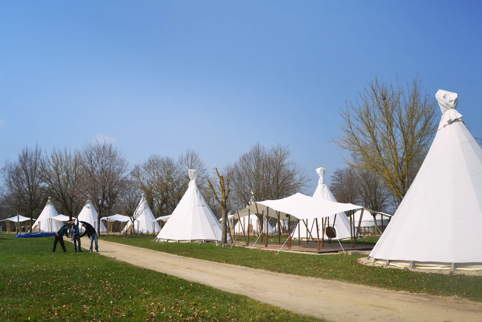 Camp de tipis blancs dressés dans un parc, l’équipe de l’atelier au travail