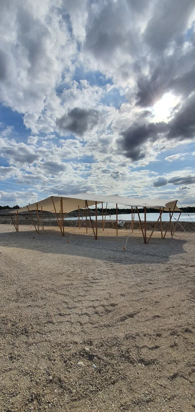 Toile nomade tendue sur une plage de galets, sous un ciel nuageux
