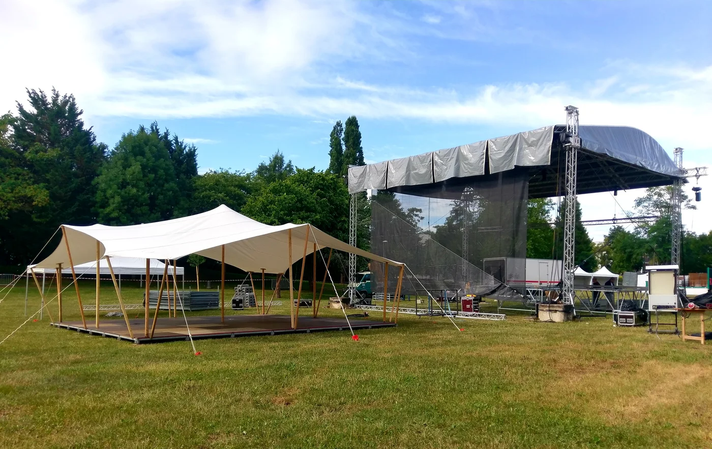 Toile nomade dressée devant une scène de festival en cours de montage