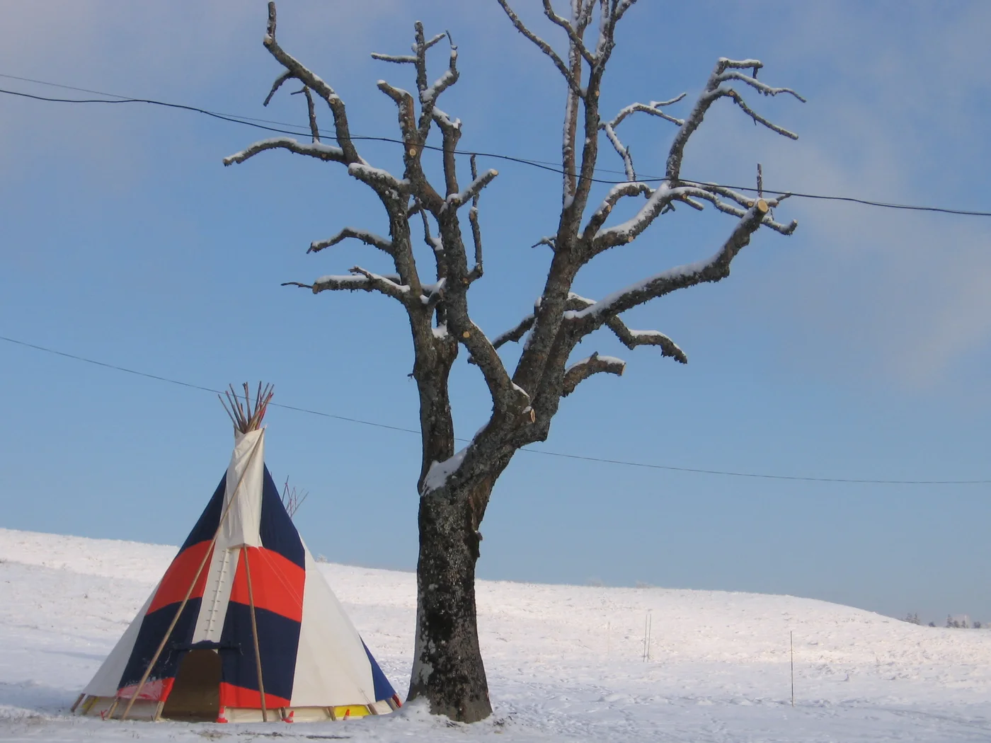 Tipi aux bandes bleues et rouges dressé sur un plateau enneigé