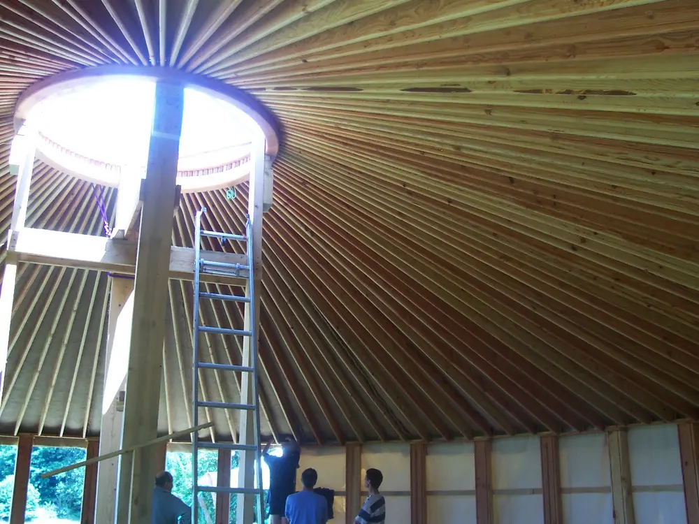 Charpente de yourte en bois clair, pendant le montage