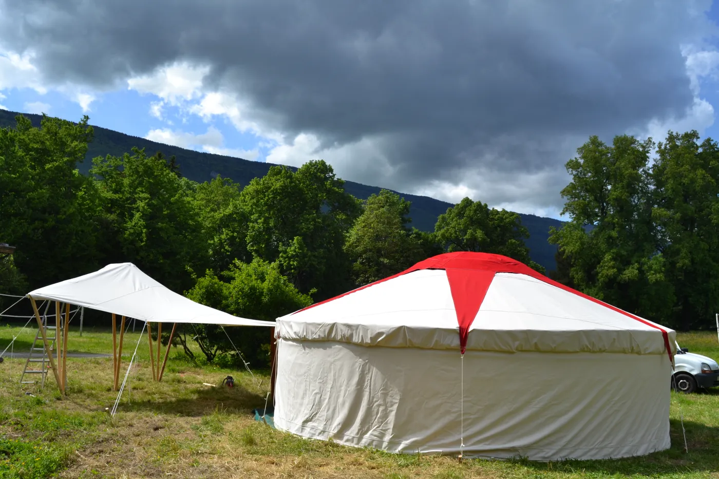Yourte à toit conique rouge et blanc, au pied des montagnes